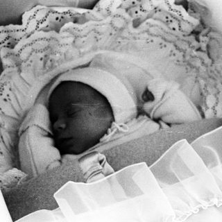 Black and white image of a baby sleeping in a crib.