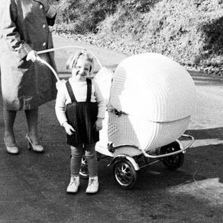 Woman and child with unusual wicker stroller on a road.