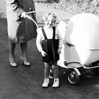 Woman and child with unusual wicker stroller on a road.