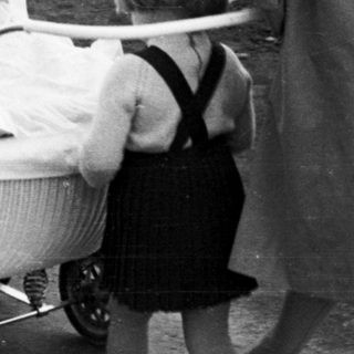 Woman and child near a vintage wicker baby carriage.