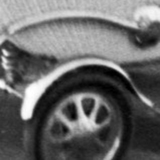 Woman pushes a wicker baby carriage along a road.