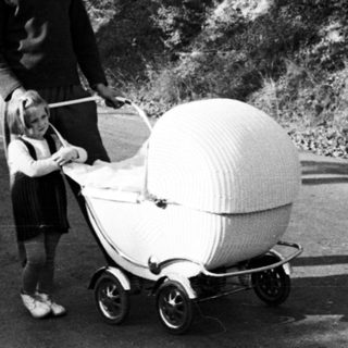 Boy pushing unusual pram along a country road.