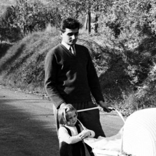 Boy pushing unusual pram along a country road.