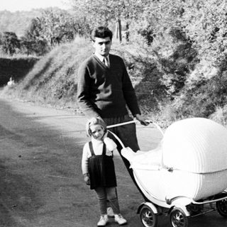 Man and child stand next to an ornate baby carriage.