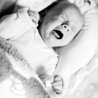 Crying baby in a blanket, black and white photo.