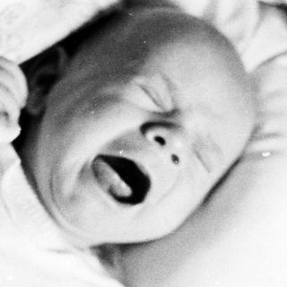 Crying baby in a blanket, black and white photo.