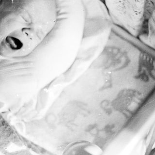 Black and white image of a baby in a crib.