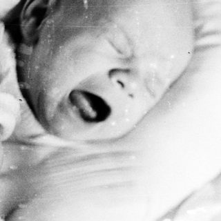 Black and white image of a baby in a crib.