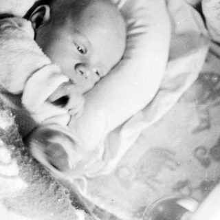 Baby sleeping in a crib, monochrome vintage photograph.