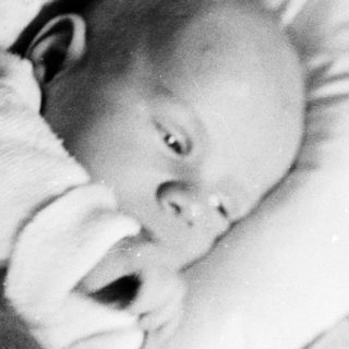 Baby sleeping in a crib, monochrome vintage photograph.