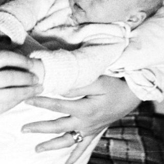Woman holding a baby, possibly in a home setting.