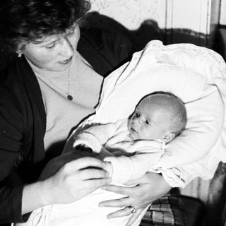 Woman holding a baby, possibly in a home setting.