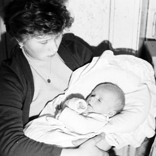 Woman holding a newborn baby wrapped in a blanket.