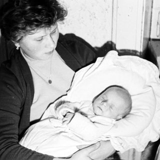 Woman holding a sleeping baby in a vintage photograph.