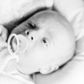 Black and white image of a baby with a pacifier.