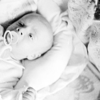 Black and white image of a baby with a pacifier.