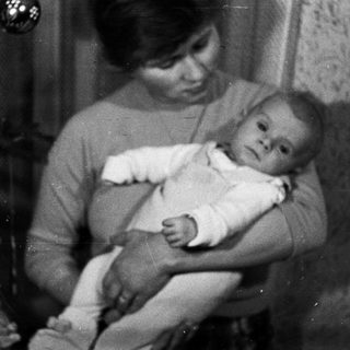 Woman holds baby, possibly during the holiday season.
