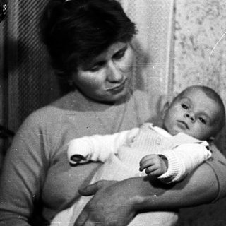 Woman holding baby in black and white photograph.