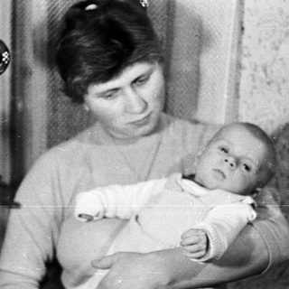 Woman holding a baby, possibly during the holiday season.