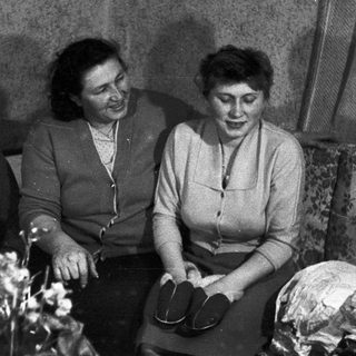 Three people sit indoors, appearing thoughtful or concerned.