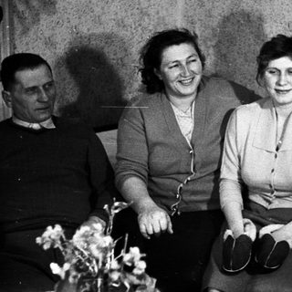 Black and white portrait of a family seated on a couch.