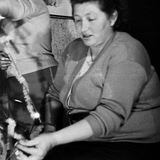 Woman decorates a Christmas tree in a vintage setting.