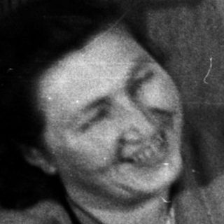 Smiling man presents flowers to a woman on a sofa.