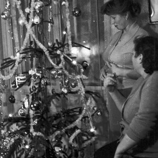 Woman decorating a small Christmas tree in a home.