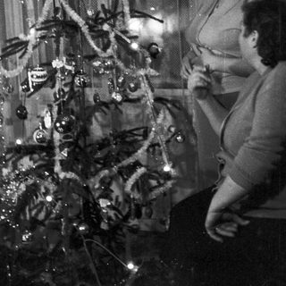 Woman decorating a small Christmas tree in a home.