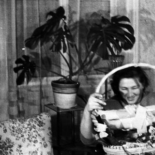 Couple smiles while holding a gift basket indoors.