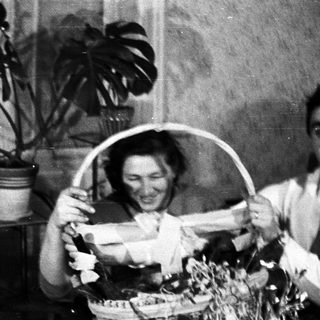 Couple smiles while holding a gift basket indoors.