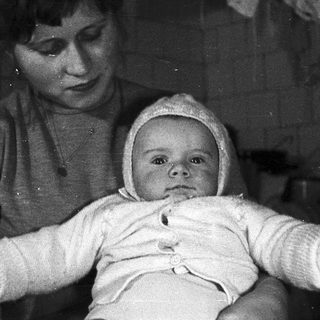 Here's a brief summary: Woman holding a baby wearing a bonnet.