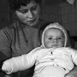Here's a brief summary: Woman holding a baby wearing a bonnet.