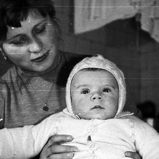 Woman holding a baby in a black and white photograph.