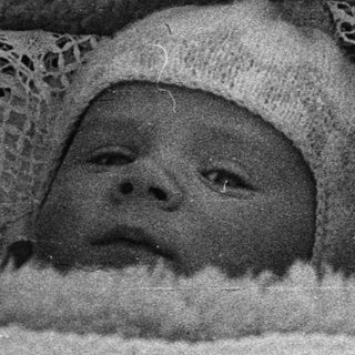 Black and white photo of a baby in a crib.
