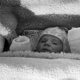 Black and white photo of a baby in a crib.