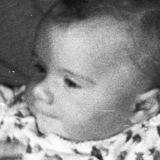 Baby held by an adult in a black and white photo.