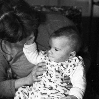 Baby held by an adult in a black and white photo.