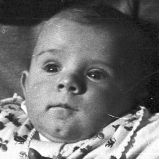 Baby being held, possibly by a parent, in black and white.