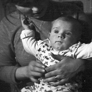 Baby being held, possibly by a parent, in black and white.