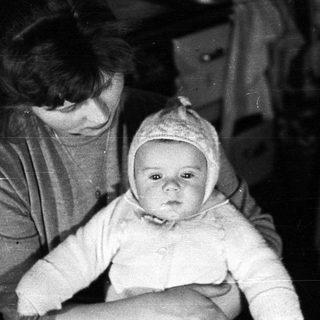 Woman holding baby wearing a bonnet, vintage photograph.