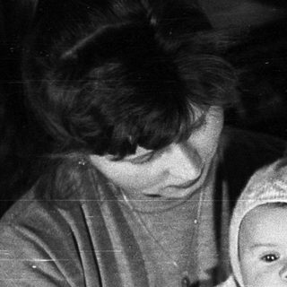 Woman holding baby wearing a bonnet, vintage photograph.