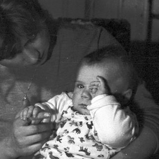 Woman holds baby, appearing in a dark, vintage photograph.