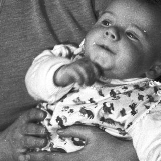 Woman holding baby, black and white portrait.