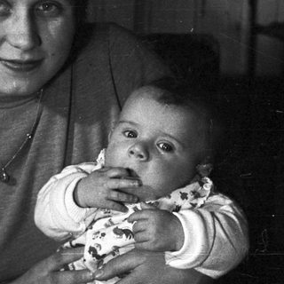 Woman holds baby, posing for a black and white portrait.