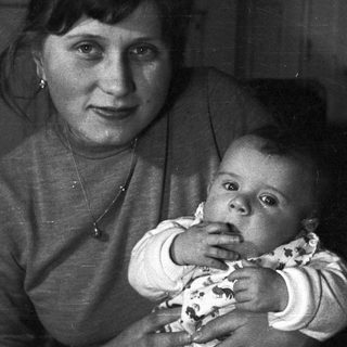 Woman holds baby, posing for a black and white portrait.