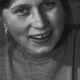 Baby held by a smiling person in a vintage photograph.