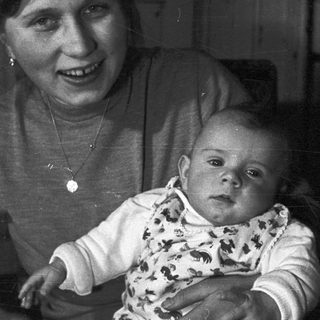 Baby held by a smiling person in a vintage photograph.