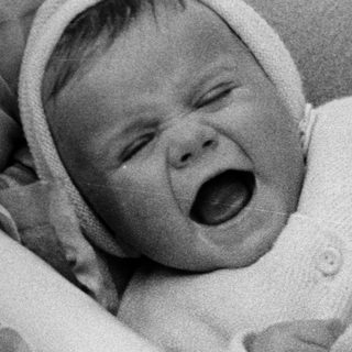Infant in a basket, appearing to cry or yell.