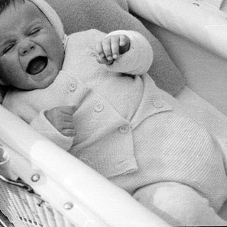 Infant in a basket, appearing to cry or yell.
